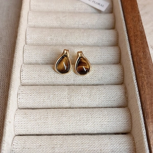 Macro detail of vintage tiger eye teardrop earrings in polished gold frame