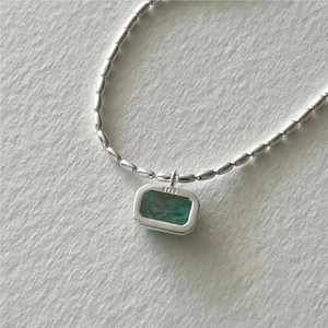 Close-up of S925 sterling silver olive bead chain with a green emerald gemstone pendant