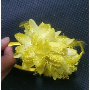 Detail of yellow flower headpiece featuring feathers, lace, and beads on a headband