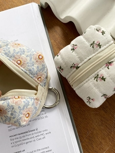 Detailed view of floral fabric earphone pouches with zipper and metal hook on desk