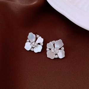 Dettaglio macro di orecchini a fiore in argento con petali di madreperla e zirconi luce