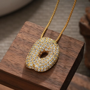 Close-up of 18K gold plated letter pendant with shimmering cubic zirconia pavé stones