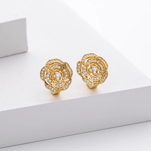 Detail view of gold camellia earrings with cubic zirconia pavé on white block
