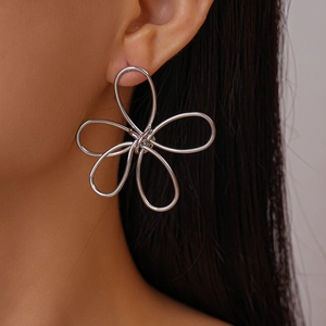 Detailed view of large silver wire hollow flower earring worn on ear with high metallic luster