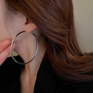 Close-up of oversized silver hoop earrings showing high-shine metal texture on model