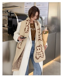 Detail view of winter knitted beige scarf featuring brown bear patterns and soft texture