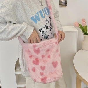 Close-up of pink plush bucket bag with heart pattern and matching shoulder strap