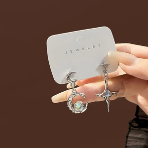 Macro shot of silver moon and star earrings with aurora stones held in hand