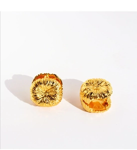 Detailed view of golden hoop earring featuring unique fireworks brushed textured surface