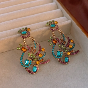 Macro shot of vintage style peacock wing earrings with colorful rhinestones in a gift box