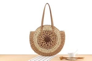 Close-up of circular handmade paper rope woven bag with hollow patterns and tan shoulder straps