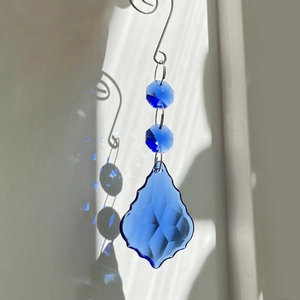 Blue maple leaf crystal suncatcher casting vibrant light reflections on wall
