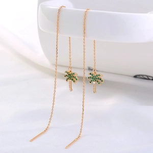 Detail of gold coconut tree earrings with green and white zircons on porcelain edge