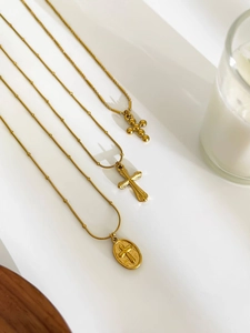 Detailed view of three vintage gold cross pendant necklaces with various chain styles