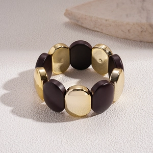 Détail d'un large bracelet élastique aux perles ovales or poli et café acrylique