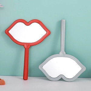 Lip shaped handheld makeup mirrors in red and grey colors on a studio background