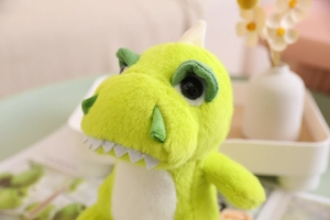 Close-up of a green plush dinosaur toy with big eyes and soft yellow belly detail