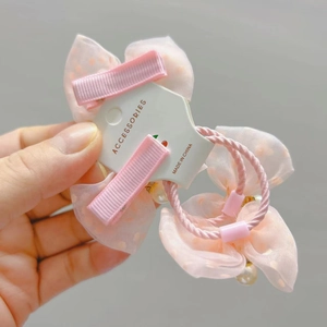 Close-up of pink polka dot lace bow hairpins with pearl pendants on a display card