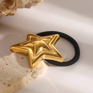 Minimalistisches Haargummi mit goldenem Stern aus Edelstahl auf beigem Naturstein