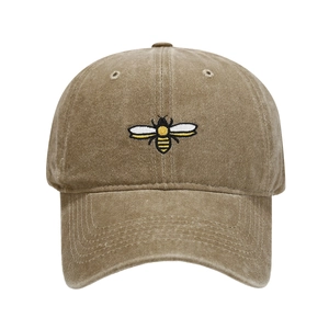 Detailed view of yellow bee embroidery on washed khaki cotton baseball cap with curved brim