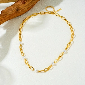 Collier en acier inoxydable plaqué or avec perles blanches sur surface texturée blanche