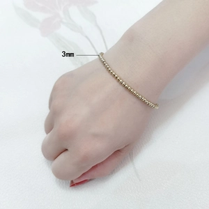 Detail of a 3mm golden stainless steel beaded bracelet on a woman's wrist with macro view