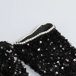 Gros plan sur le tissu à paillettes noires avec bordure en strass argentés brillants