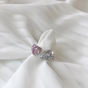 Détail macro d'une bague ouverte avec cœur rose et zircon poire sur un anneau argenté