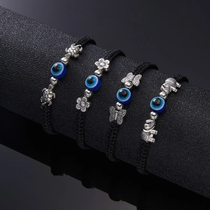 Close-up of woven evil eye bracelets with silver turtle and elephant charms
