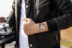 Close-up of rose gold skeleton mechanical watch worn by man on leather motorcycle gear