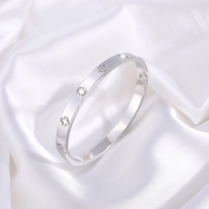 Detail of silver bangle showing hollow clover motifs and sparkling zircon inlay
