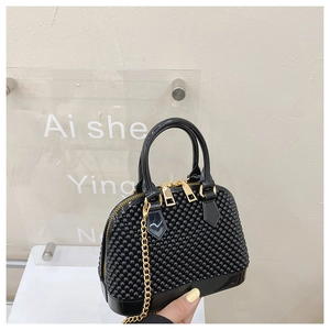 Detail of black shell-shaped jelly bag with beaded studs and gold chain strap
