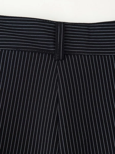 Détail macro du pantalon de costume noir à rayures montrant le tissu et les coutures