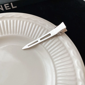 Vue macro de barrettes à cheveux minimalistes en métal argenté sur assiette céramique