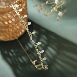 Detailed view of vintage gold leaf headband with cat-eye stones and small pearls