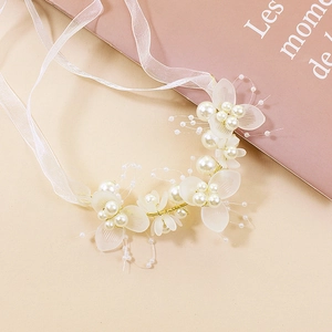 Détail de la coiffe de demoiselle d'honneur avec pétales blancs, perles et ruban de soie