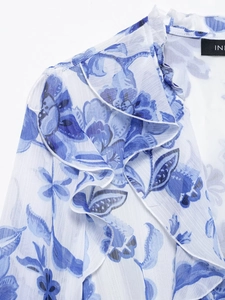 Détail de l'encolure à volants et imprimé floral bleu sur robe midi en mousseline