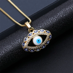 Macro shot of gold Evil Eye pendant with blue enamel and sparkling crystal accents