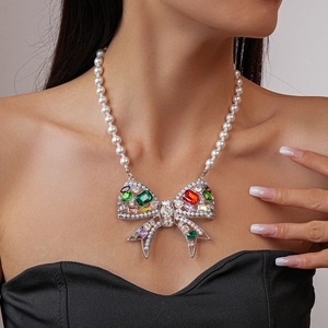 Detailed view of luxury pearl necklace with colorful gemstone bow on a model neckline