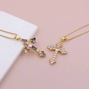 Close-up of bohemian cross necklaces with colorful zircon stones on pink marble background