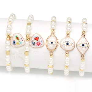 Detail of beaded pearl bracelets featuring evil eye charms and graffiti heart pendants