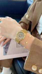 Close-up of golden watch and bracelet set on wrist with elegant rhinestone bezel