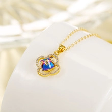 Macro detail of a gold clover necklace featuring a radiant purple crystal and pavé accents
