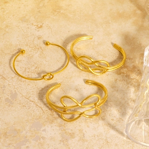 Ensemble de trois bracelets nœuds géométriques plaqués or 18K sur surface en pierre