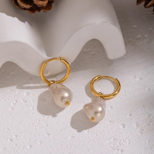 Detailed close-up of gold hoop earrings with irregular white baroque pearl pendants