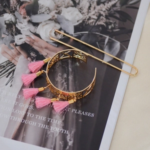 Vintage hollow gold hair crown set with pink tassels on magazine background, top view