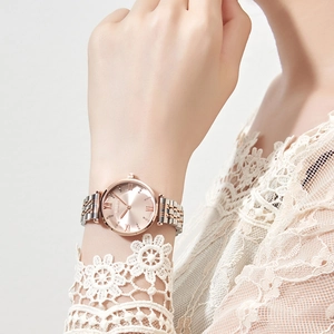 Elegant rose gold and silver watch on woman wrist with lace sleeve and crystal details