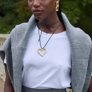 Gold hollow heart pendant necklace and drop earrings set worn by model in nature