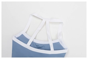 Macro-detail van mistblauwe yoga top met witte bies en multi-strap gekruist rugontwerp