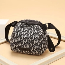 Detail of monogram print shell bag with black leather trim and wide shoulder strap